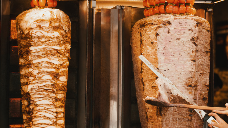 Person slicing Turkish doner kebab from spit