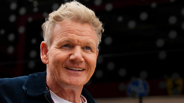 Gordon Ramsay smiles against a dark background