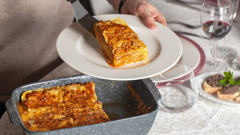 Person serving a slice of homemade, meaty lasagna