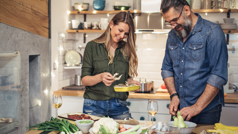 man and woman preparing a meal together in kitchen
