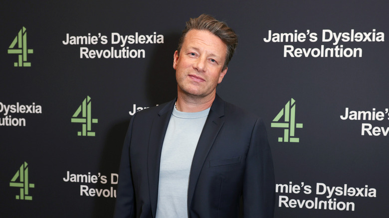 Jamie Oliver tilts his head at a red carpet event for dyslexia