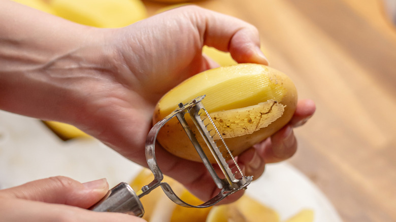 Someone peels a potato