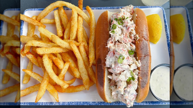 A classic lobster roll, on a plate next to some fries