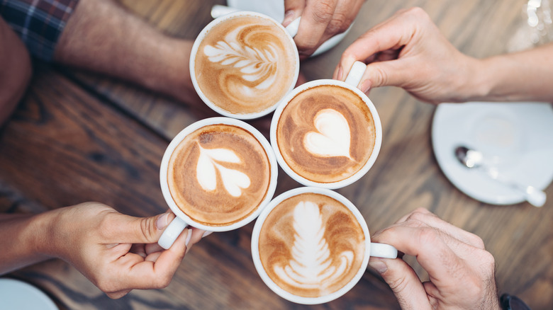 Hands holding mugs filled with latte art