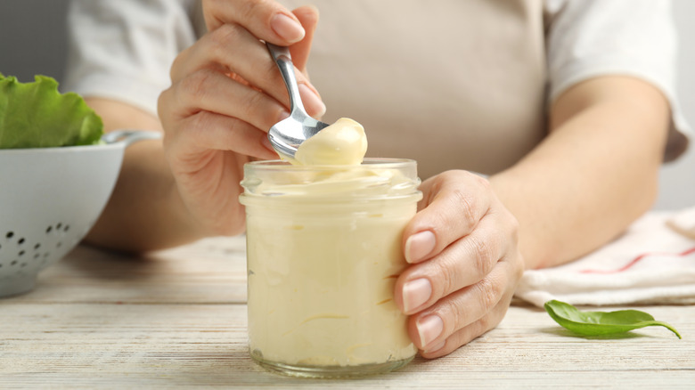 Woman scooping mayo out of a jar with a spoon