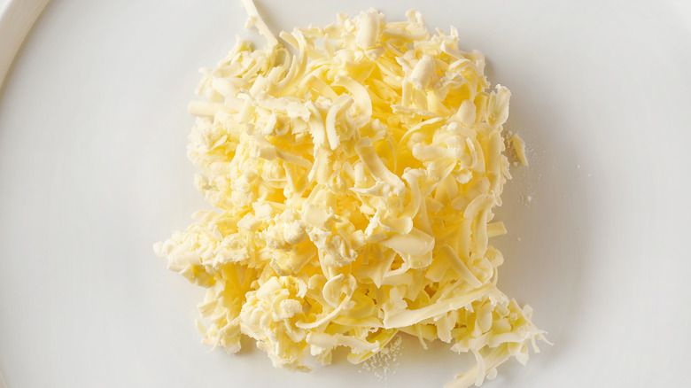 Grated butter sits in the middle of a white plate