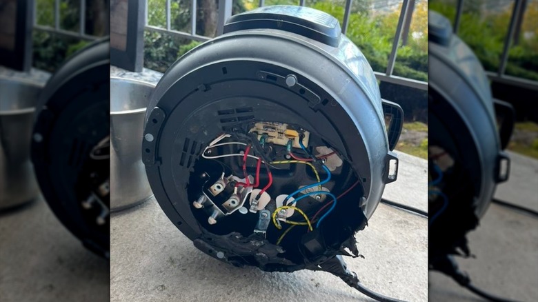 An Instant Pot sits on its side, revealing the open wiring underneath