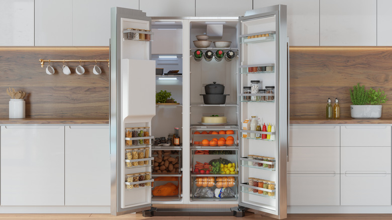 A refrigerator's doors are open, revealing the food inside