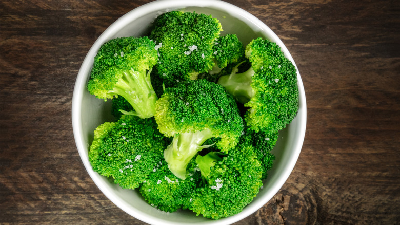 bowl of cooked broccoli on a wooden table