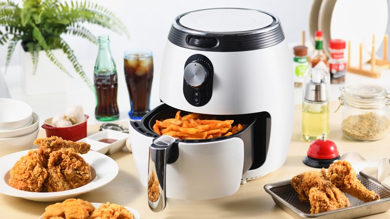 An air fryer next to plates of food