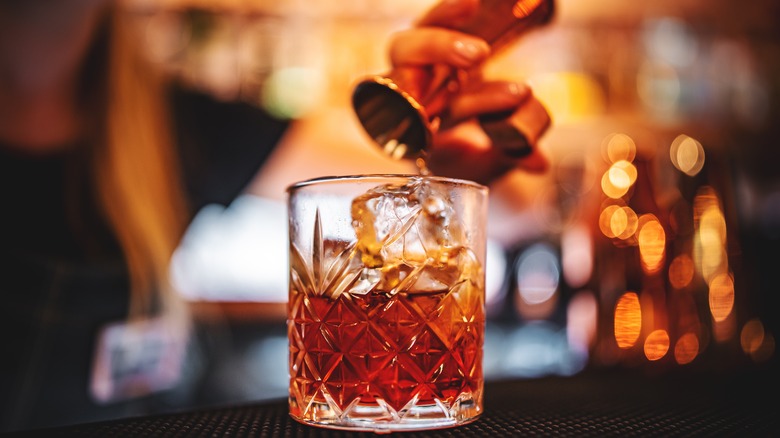 Pouring cocktail into crystal glass