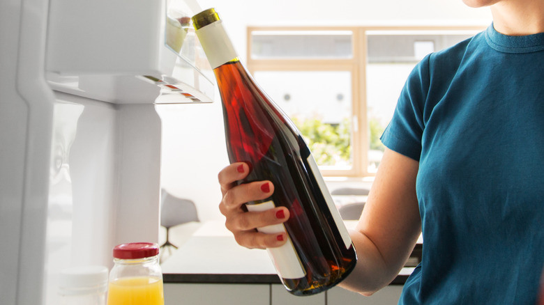 Person storing vermouth in fridge