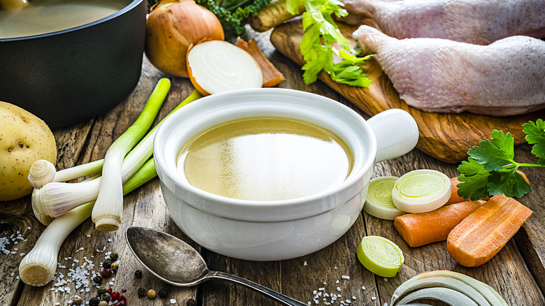 bowl of chicken stock surrounded by vegetables