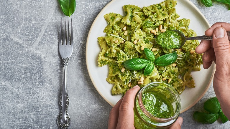 Spooning pesto on bowtie pasta