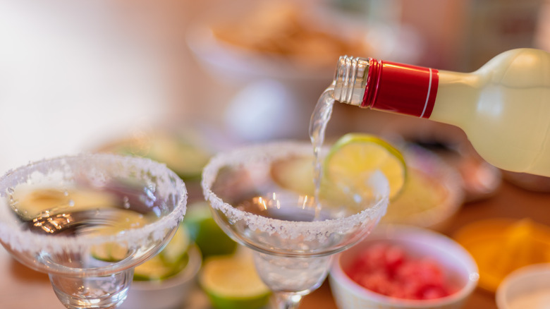 pouring bottled margaritas into a glass