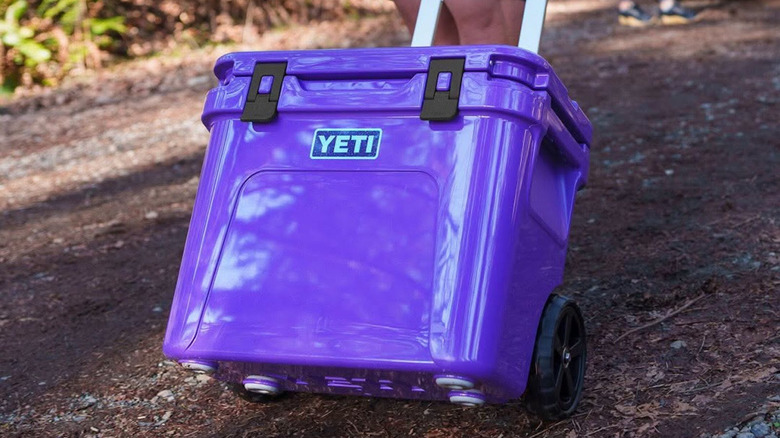 Someone pulls a Yeti cooler on wheels by a handle.