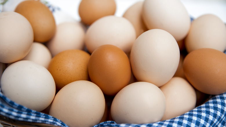 Multi-hued eggs in a basket with a blue and white checked cloth