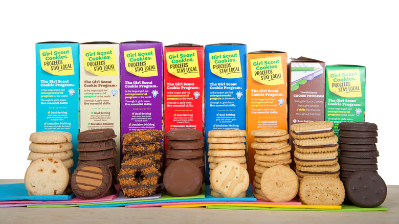 Different types of Girl Scout cookies stacked next to each other in front of their boxes.