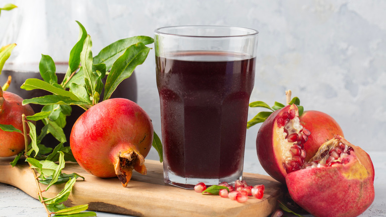 A glass of pomegranate juice is on a cutting board.