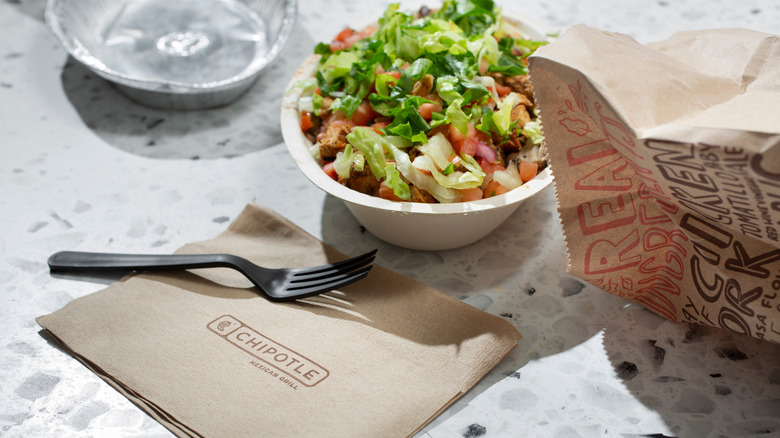 A Chipotle bowl next to a napkin and fork