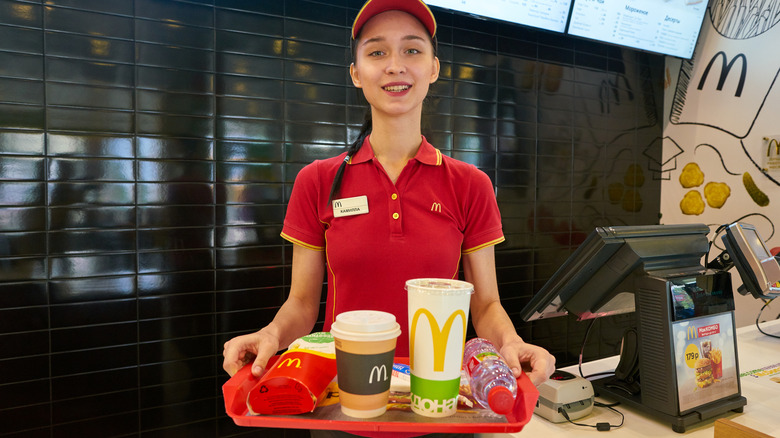 A McDonald's employee holding a tray of McDonald's food and drinks in the restaurant