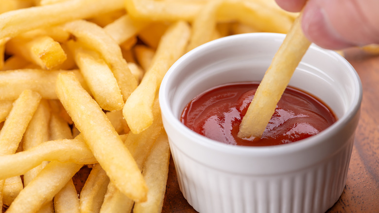 Dipping fries into ketchup.