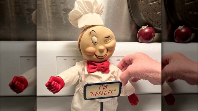 A hand holds up a McDonald's Speedee porcelain doll.