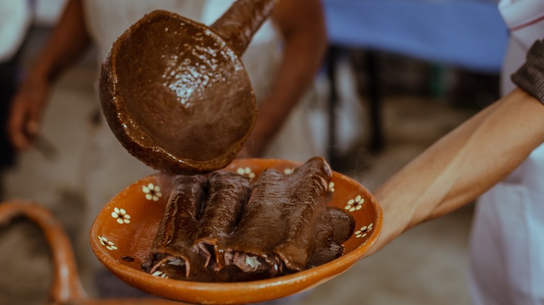 Pouring mole sauce on enchiladas