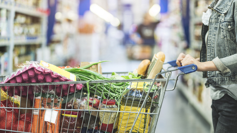 Woman pushing full grocery cart in aisle