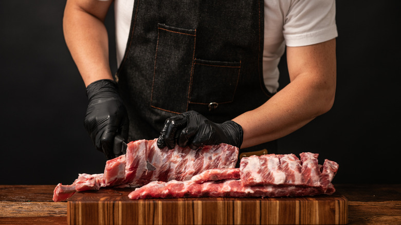 Butcher breaking apart pork ribs.