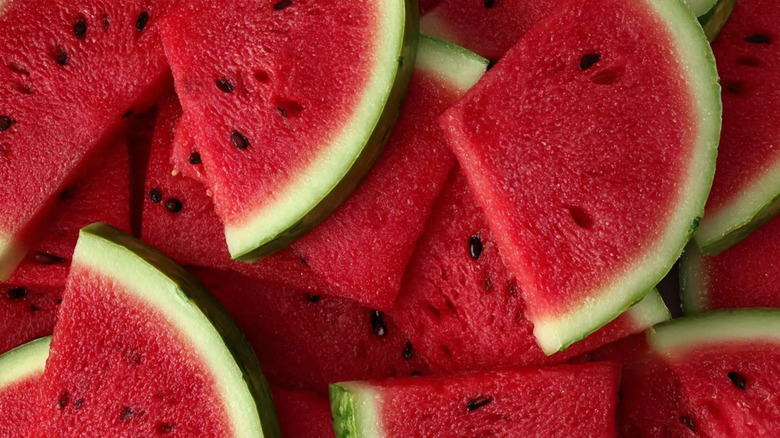 Triangular slices of seeded watermelon in a pile.