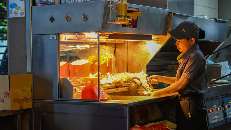 A McDonald's employee serves portions out fries in the kitchen