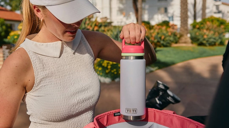 Someone holds a Yeti water bottle by its handle.