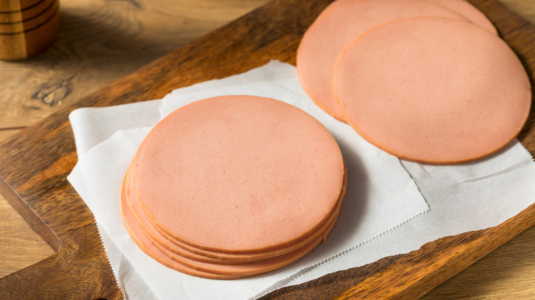Slices of round, deli-style pork bologna on a wooden cutting board