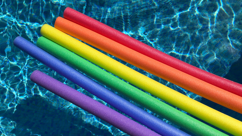 Rainbow colored pool noodles in pool