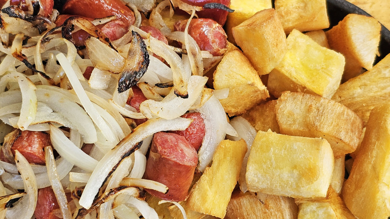 Sausage, potatoes, and onions sit in a skillet, close-up