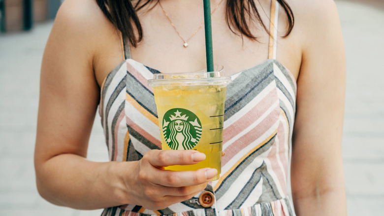 Person holding a Starbucks lemonade in hand.