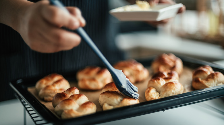 A person brushing butter on biscuits
