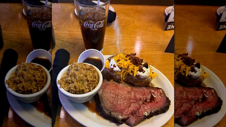 Texas Roadhouse prime rib with a baked potato topped with sour cream, cheese and bacon bits, and a small bowl of rice