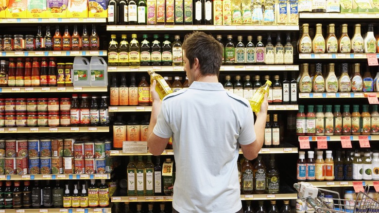 Man comparing oils at the grocery store