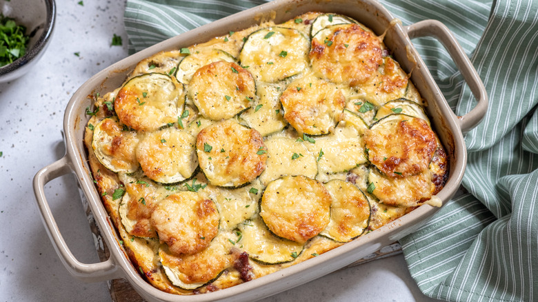 cheesy zucchini casserole in pan is topped with fresh herbs
