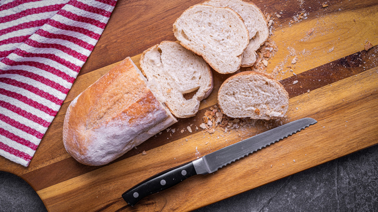 Serrated knife on a cutting board with sliced bread