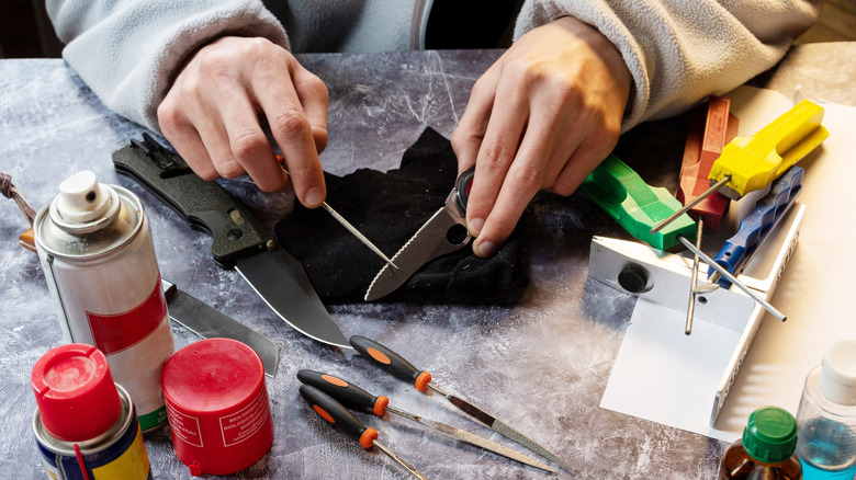 Person sharpening a serrated knife by hand