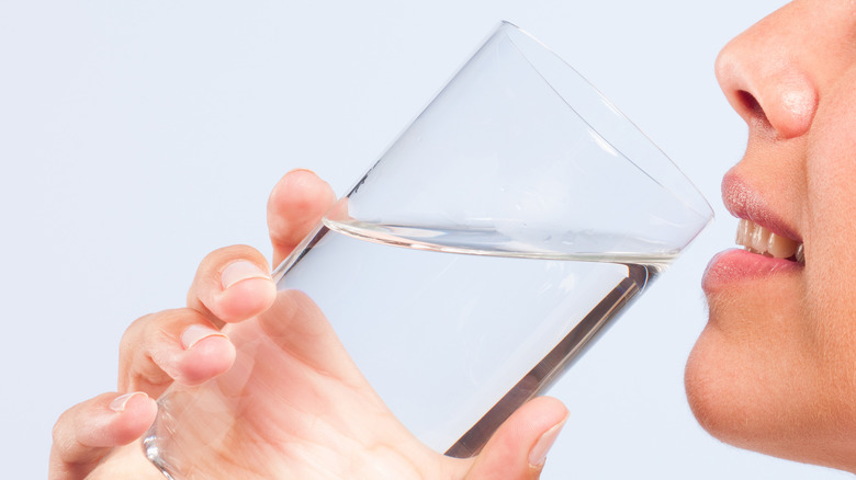 woman tasting water from glass