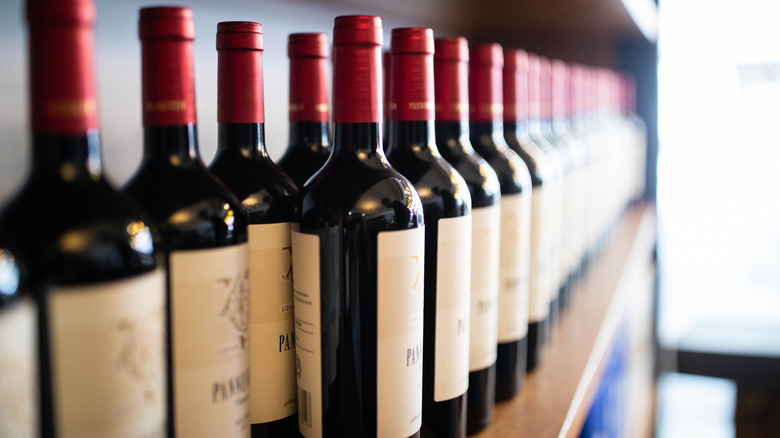 A row of red wines on a wooden shelf