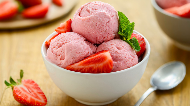 Homemade strawberry ice cream in a bowl on the wooden table. Healthy summer dessert. Selective Focus