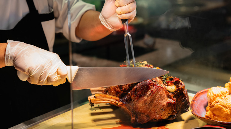 A chef slicing a prime rib roast.
