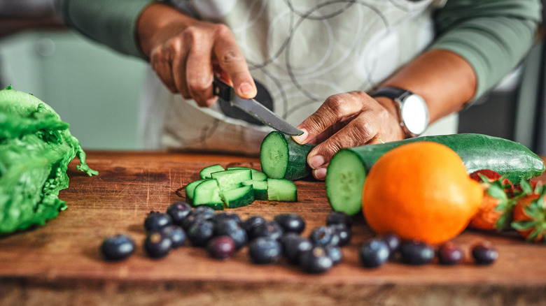 A home cook chopping several vegetables.