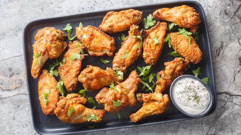 Crispy chicken wings are arrayed on a platter with dipping sauce