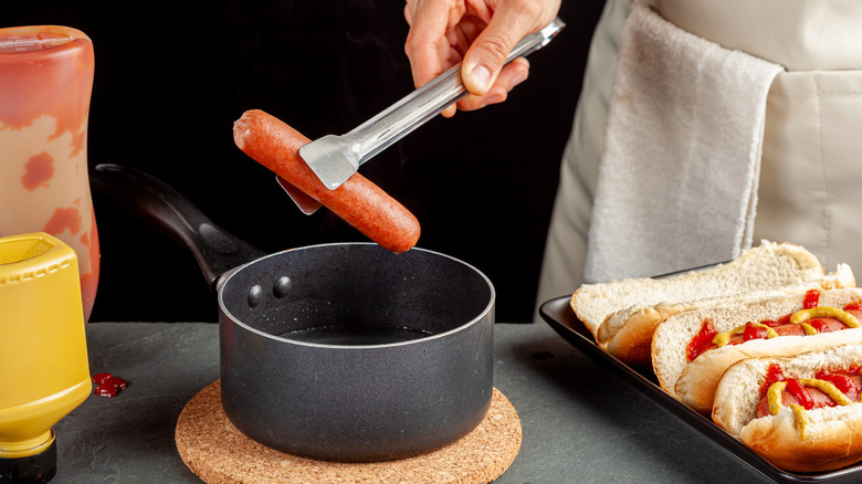 Removing a hot dog from a pan of boiling liquid 